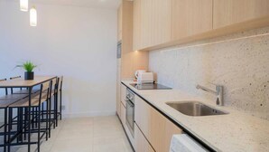 A modern kitchen with wooden cabinets, a granite countertop, stainless steel sink, and pendant lighting. - Charming Apartment - 2bdr/6p - Saint Tropez/port (Saint-Tropez)