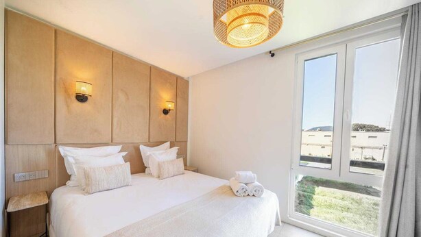 A hotel room with a large bed, two wall-mounted lights, a window with a view, and a ceiling light fixture. - Charming Apartment - 2bdr/6p - Saint Tropez/port (Saint-Tropez)