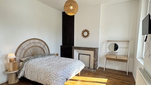 Una camera da letto con un letto, pavimento in legno, TV a parete e camino.