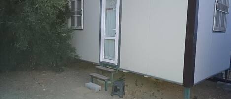 A single-story mobile home with a front door, two windows, and a small porch area.