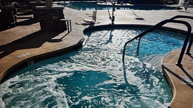 A hot tub with a stone wall and a pool in the background. - Resort with 1 bedroom and AC in delightful Las Vegas (Las Vegas)
