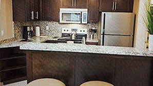 A kitchen with dark cabinets, a microwave, a stove, a refrigerator, and two stools. - Resort with 1 bedroom and AC in delightful Las Vegas (Las Vegas)