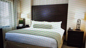 A hotel room with a large bed, a nightstand with a lamp, a dresser, and a window with curtains. - Resort with 1 bedroom and AC in delightful Las Vegas (Las Vegas)