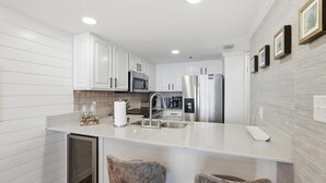 Une cuisine moderne avec des meubles blancs, des appareils en acier inoxydable et un îlot central.