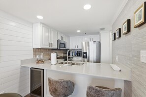 A modern kitchen with white cabinetry, stainless steel appliances, and a central island. - Diamonds on the Water- Luxury 16th-Floor Gulf Views (Santa Rosa Beach)