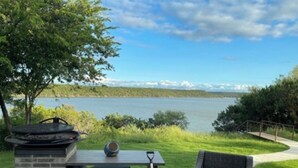 En terrasse med grill, bord og stol med udsigt over en sø.