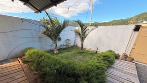 Ein Gartenbereich mit Holzterrasse, Topfpflanzen und einer weißen Mauer.