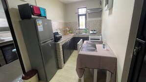Eine kleine Küche mit Kühlschrank, Mikrowelle, Toaster, Spüle und einem Tisch mit Tischdecke.