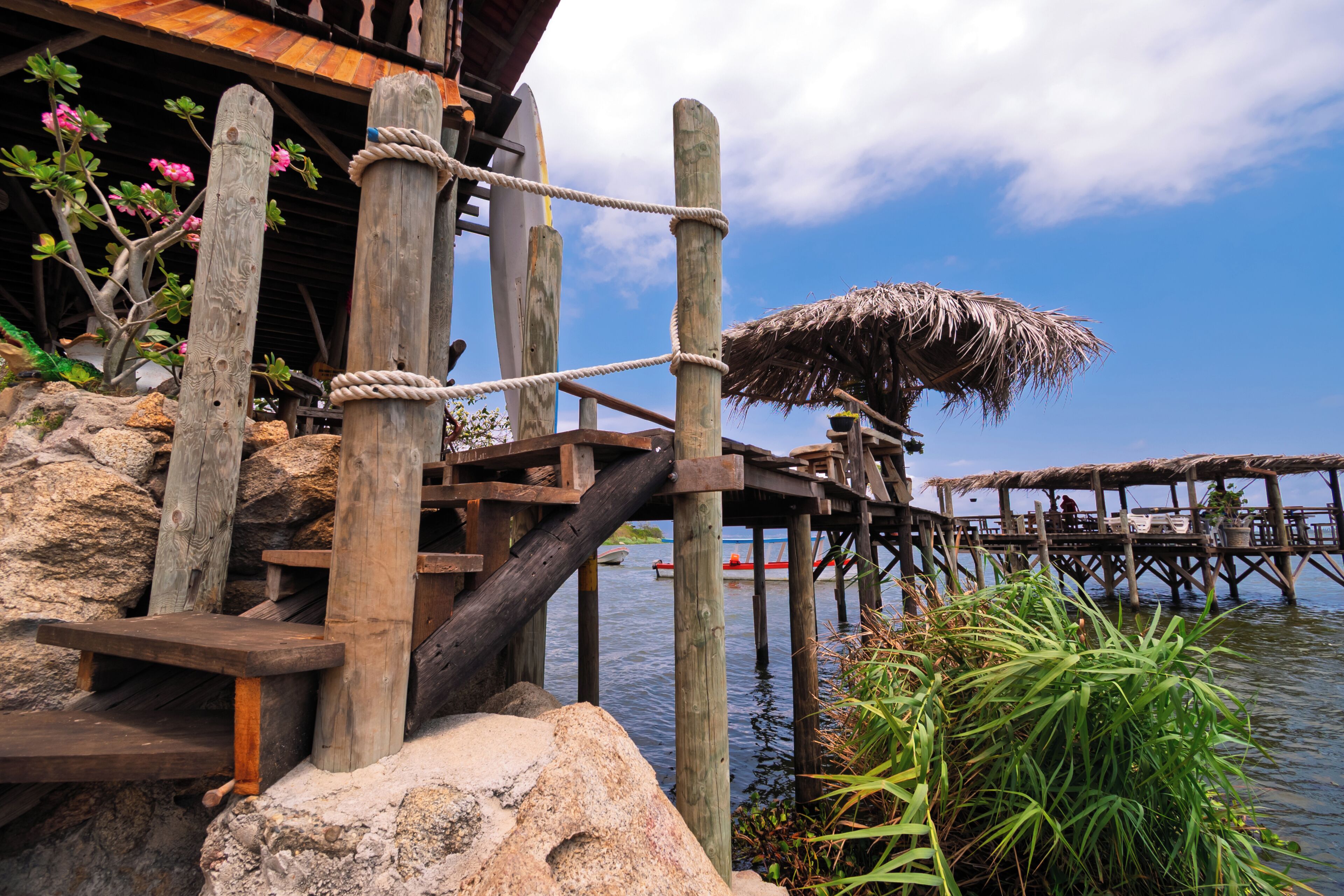 A wooden pier with a thatched roof, wooden railings, and a view of the water.