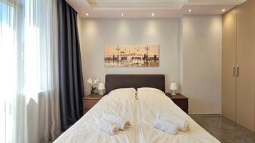 A hotel room with a large bed, a painting on the wall, a nightstand with a lamp, and a wardrobe.