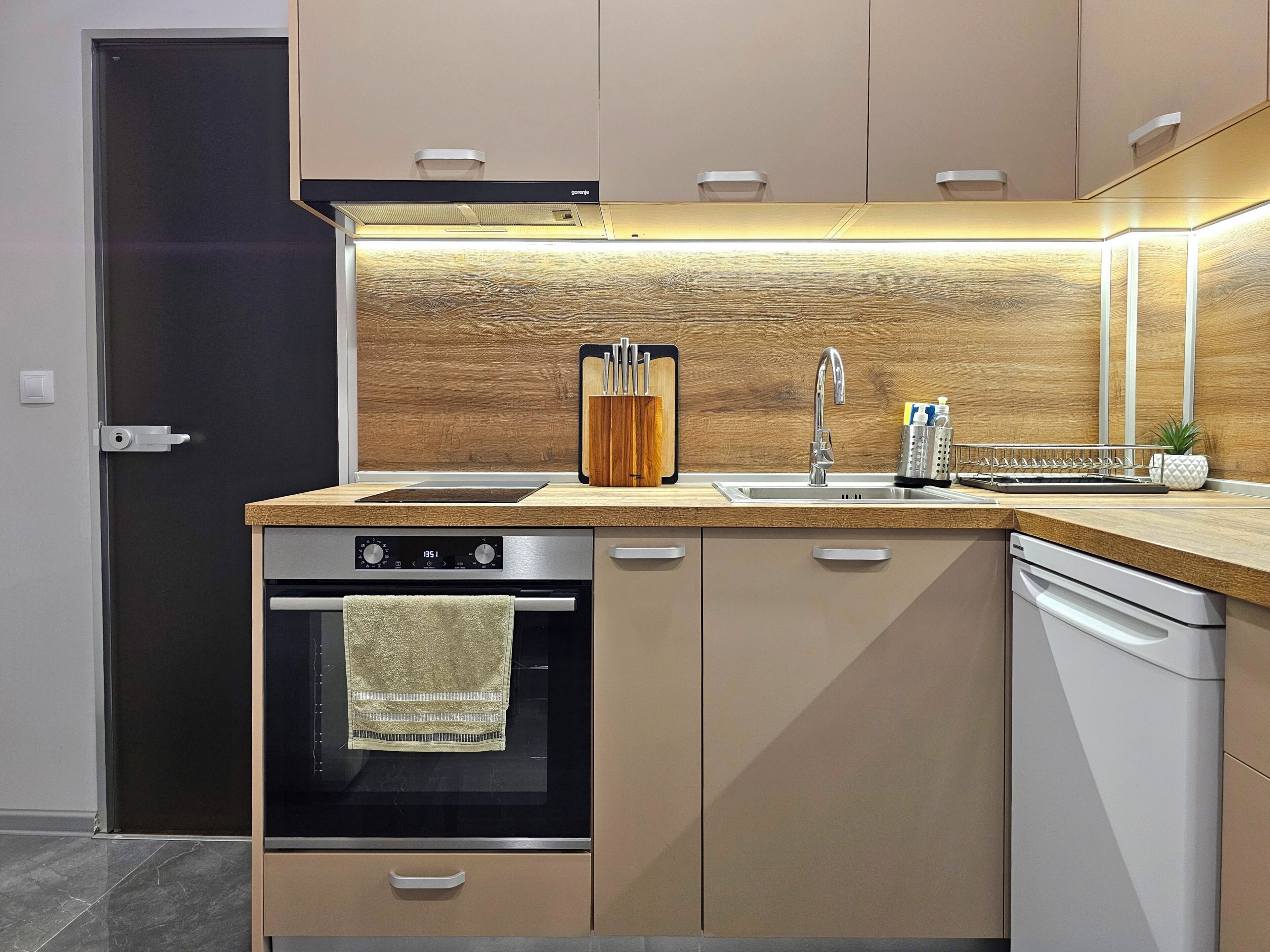Eine moderne Küche mit Backofen, Geschirrspüler, Spüle und einer Holz Arbeitsplatte.