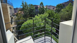 A balcony with a metal railing overlooking a residential area with trees and buildings.