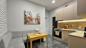 A modern kitchen with a built-in oven, a wooden countertop, and a dining area with a gray sofa and a small table.