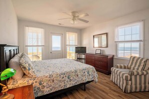A bedroom with a bed, a chair, a dresser, a television, and a ceiling fan. - On Porpoise- Oceanfront, Pet Friendly (North Topsail Beach)