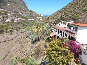 A hillside property with a white building featuring balconies and a red roof, surrounded by vegetation and a mountainous backdrop. - Casa Lara Hermigua - Studio GRAND CANYON with terrace (Hermigua)