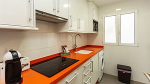 Keittiössä on valkoiset kaapit, oranssi työtaso, kahvinkeitin, mikroaaltouuni, pesuallas ja roskakori.