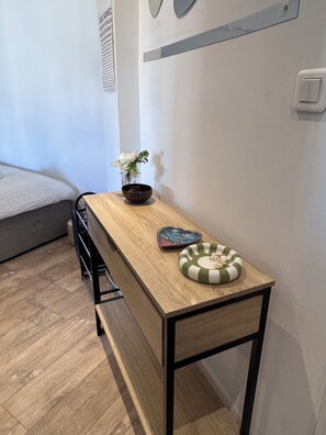 A room with a bed, a wooden table with a bowl and a heart-shaped tray, a small vase with flowers, and a wall-mounted light switch. - Charming apartment - Centre Cannes - Near Palais des Festivals and beaches (Cannes)