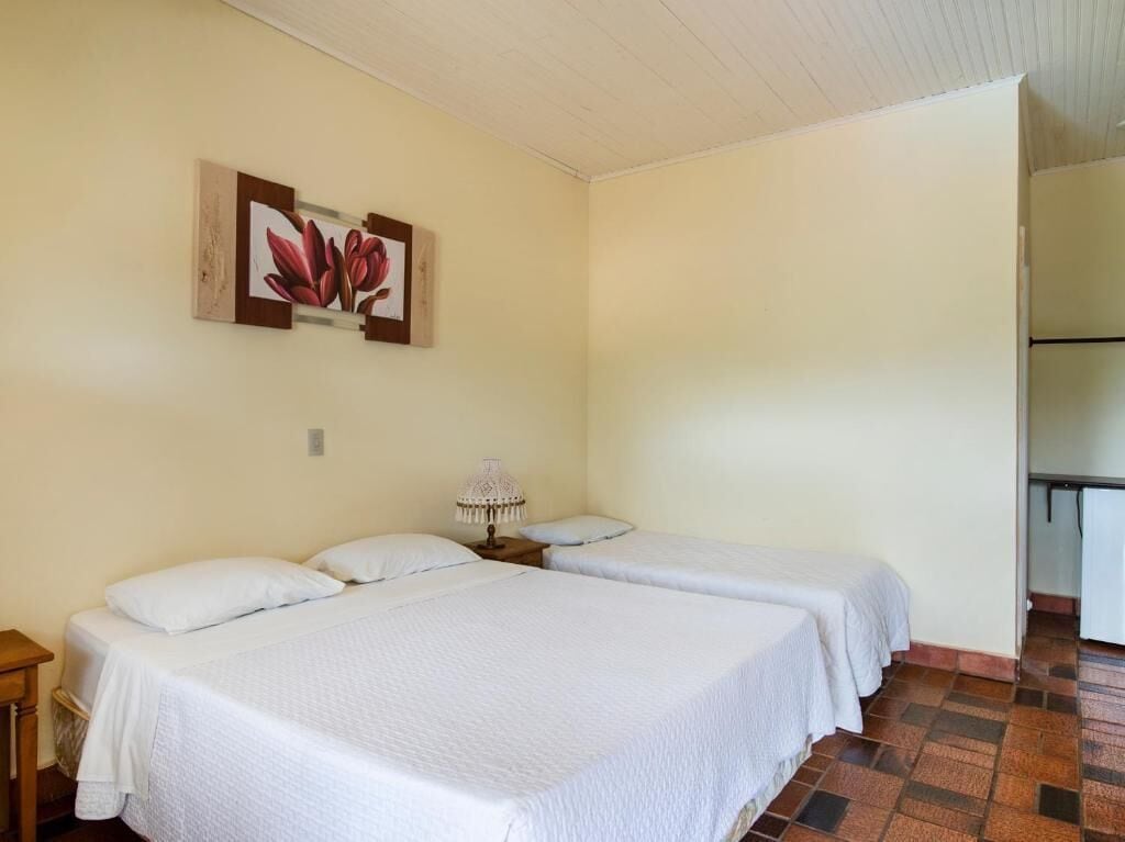 A room with two beds, a nightstand, a lamp, and a painting on the wall.
