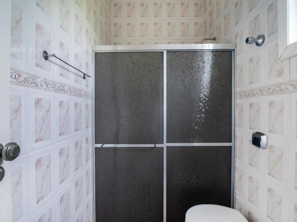 A bathroom with a shower enclosure, tiled walls, and a toilet.