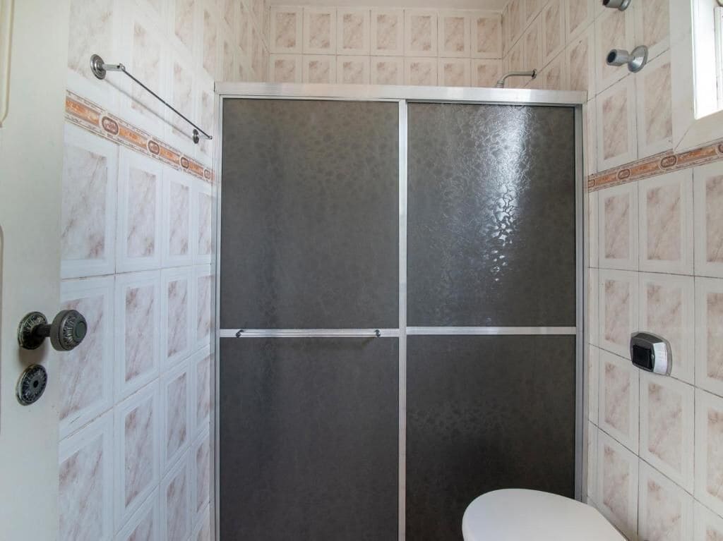 Un baño con cabina de ducha, paredes con azulejos y un inodoro.