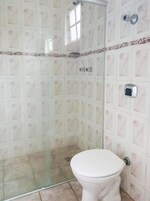 A bathroom with a glass shower enclosure, a toilet, and tiled walls.