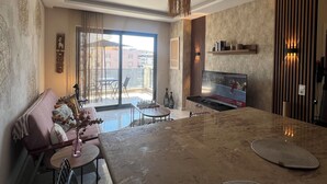 Una sala de estar moderna con un televisor grande, un comedor y un balcón con vistas a edificios.