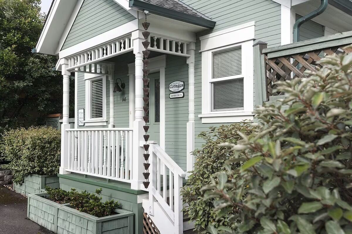 A two-story house with a porch, a sign indicating it is a cottage, and a mailbox.