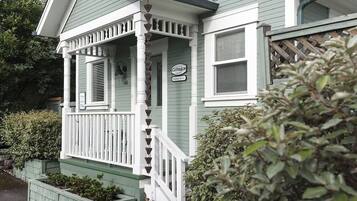 A two-story house with a porch, a sign indicating it is a cottage, and a mailbox.