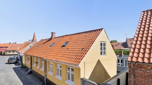 En gul bygning med rødt tegltag, et lille vindue og en dør.
