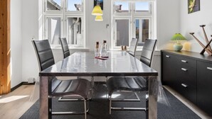 En moderne spisestue med et glasbord, sorte stole og et sort skab.
