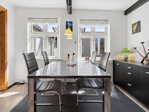 Une salle à manger moderne avec une table en verre, des chaises noires et un buffet noir.
