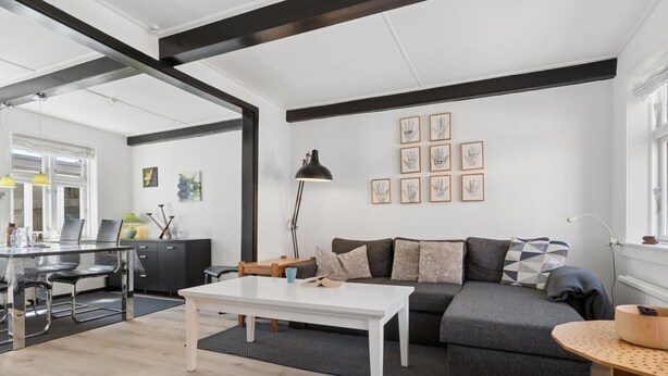 En moderne stue med sofa, sofabord og et billede på væggen.