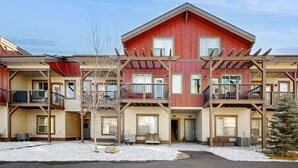 A multi-story building with balconies, a snow-covered ground, and a clear sky.