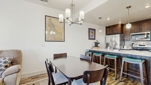 A modern kitchen with a central island, bar stools, and a dining table with chairs.