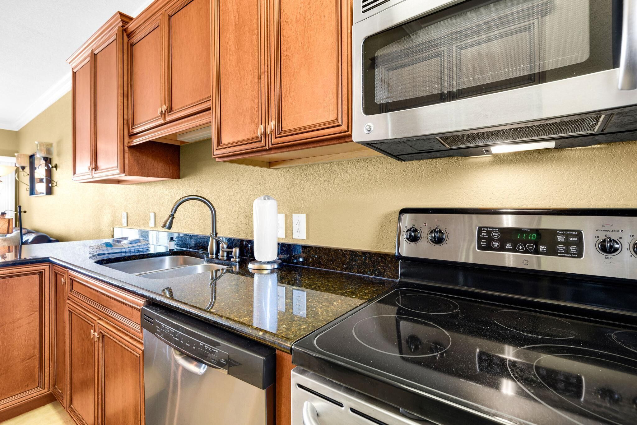 A kitchen with wooden cabinets, a stainless steel dishwasher, a microwave, and a stove.