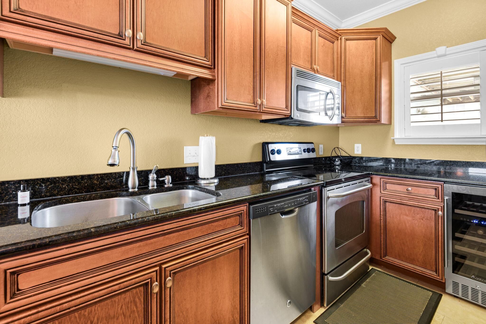 A kitchen with wooden cabinets, stainless steel appliances, a double sink, and a window with blinds.