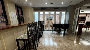 A spacious room with a marble floor, a piano, a bar area, and a view through large glass doors. - Flat em Moema com Cozinha (São Paulo)