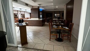 A modern hotel lobby with a marble floor, wooden reception desk, and dining area with tables and chairs. - Flat em Moema com Cozinha (São Paulo)