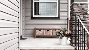 A house entrance with a stone staircase, a wooden bench, and a potted plant.