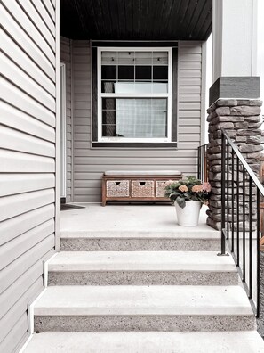 A house entrance with a stone staircase, a wooden bench, and a potted plant.