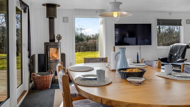 A modern living room with a large wooden dining table, a fireplace, and a television. - "Jytte" - 800m to the fjord by Interhome (Roslev)