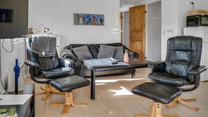 A modern living room with a sofa, two armchairs, a coffee table, and a wooden door. - "Jytte" - 800m to the fjord by Interhome (Roslev)