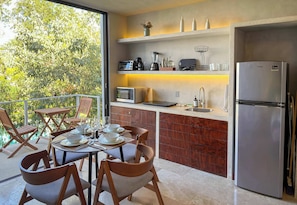 A modern kitchen with a built-in refrigerator, microwave, and coffee maker. There is a dining area with wooden chairs and a table set for two. - Piece of Paradise: 2BR Apartment with Private Pool in Tulum (Tulum)