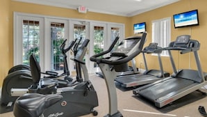 Een fitnessruimte met loopbanden, een elliptische trainer en een hometrainer.