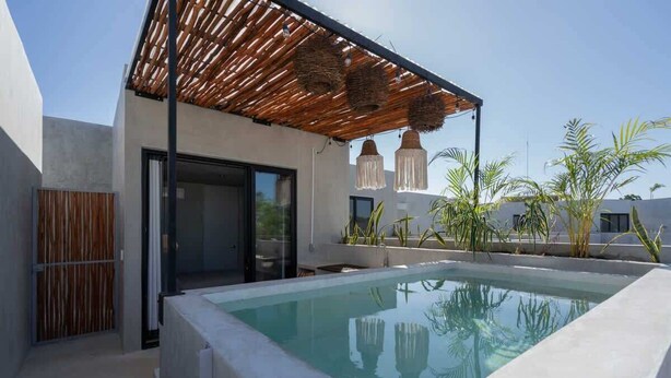 Ein Pool auf dem Dach mit einer Pergola, Sitzgelegenheiten im Freien und tropischen Pflanzen.