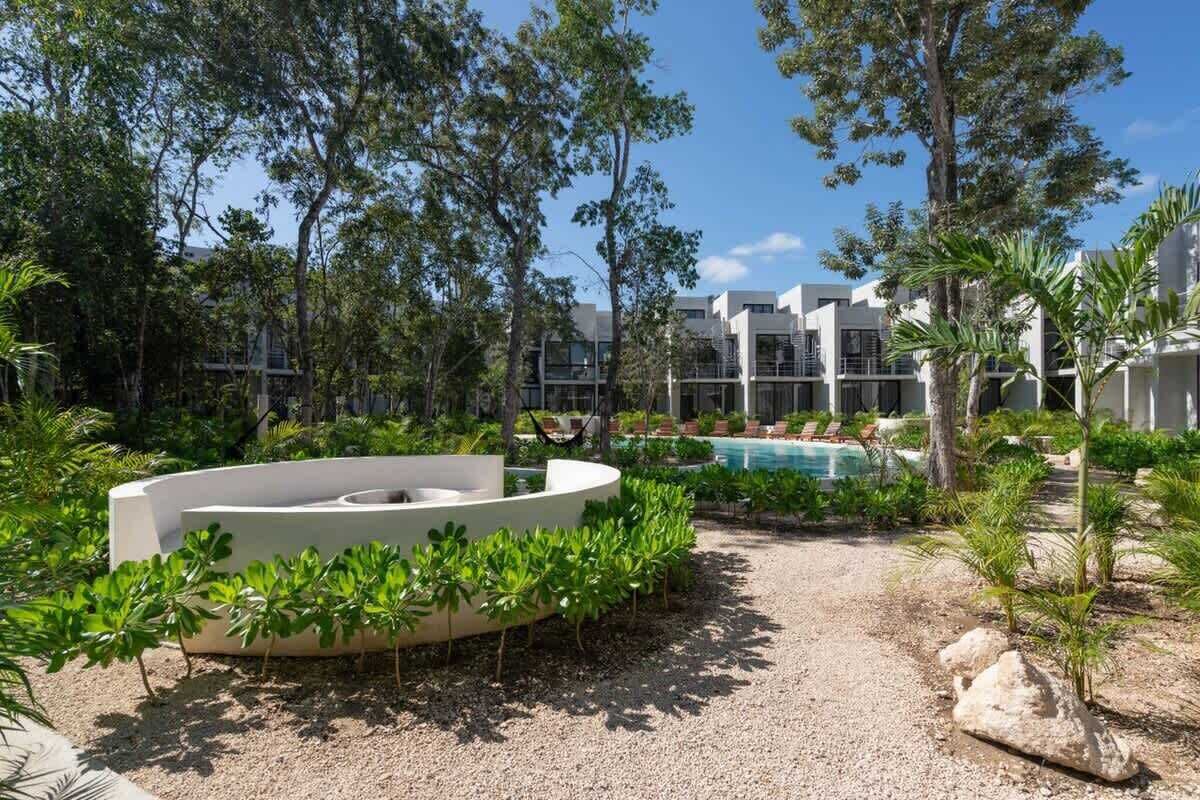 A pool area with a circular seating structure, surrounded by greenery and trees.