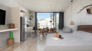 Ein modernes Hotelzimmer mit Bett, Küchenzeile, Essbereich und einem Balkon mit Blick.