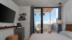 Ein Schlafzimmer mit Bett, Fernseher, Schreibtisch, Stuhl und einem Balkon mit Blick.