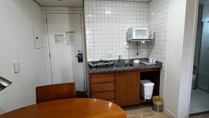 A kitchen with a microwave, sink, and wooden cabinets. - Elegance Suítes Ibirapuera Moema (São Paulo)