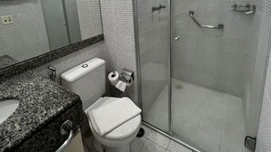 A modern bathroom with a glass shower enclosure, a toilet, and a granite countertop. - Elegance Suítes Ibirapuera Moema (São Paulo)